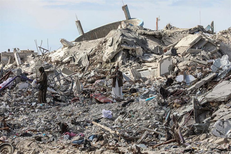 Archivo - Imagen de archivo de palestinos en el sur de la Franja de Gaza junto a escombros de edificios destruidos por ataques del Ejército de Israel