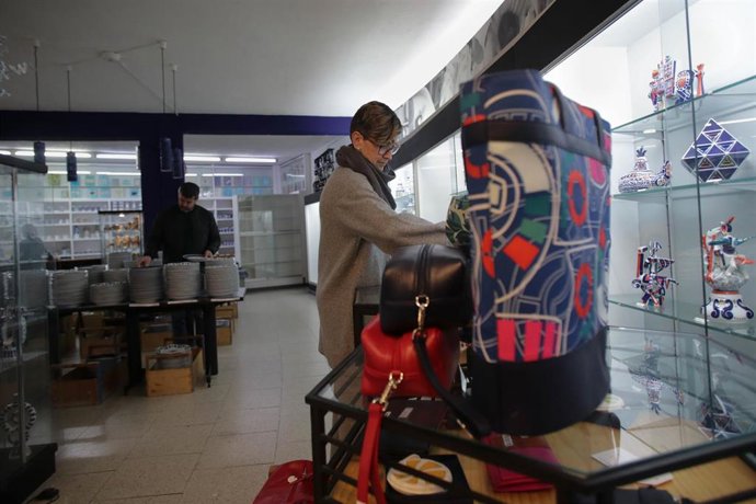 Archivo - Una mujer revisa unos complementos a la venta durante la primera jornada de estas rebajas, en el entorno de la Planta Circular de Sargadelos.
