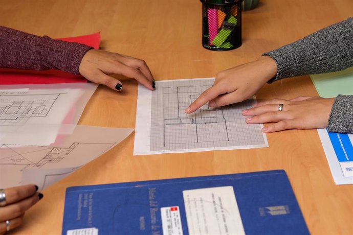 Archivo - Dos chicas señalan el plano de una vivienda.