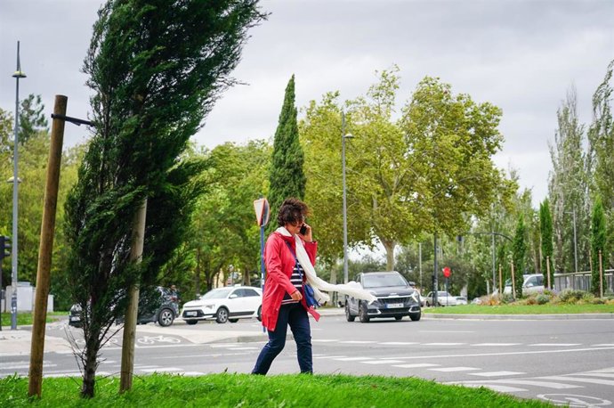 Archivo - Una mujer camina por la calle un día de viento.