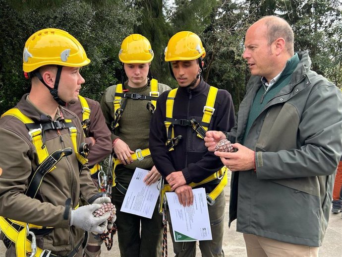El delegado territorial de Sostenibilidad y Medio Ambiente en la provincia de Cádiz, Óscar Curtido, junto a alumnado de la primera promoción de la escuela de piñeros en los montes públicos de los Alcornocales.
