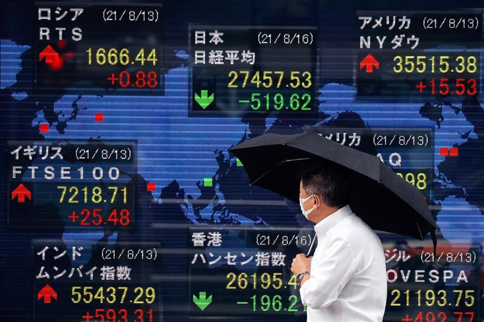 Archivo - 16 August 2021, Japan, Tokyo: A man holding an umbrella walks in front of an electric board showing the Nikkei index for the Tokyo Stock Exchange. Photo: James Matsumoto/SOPA Images via ZUMA Press Wire/dpa