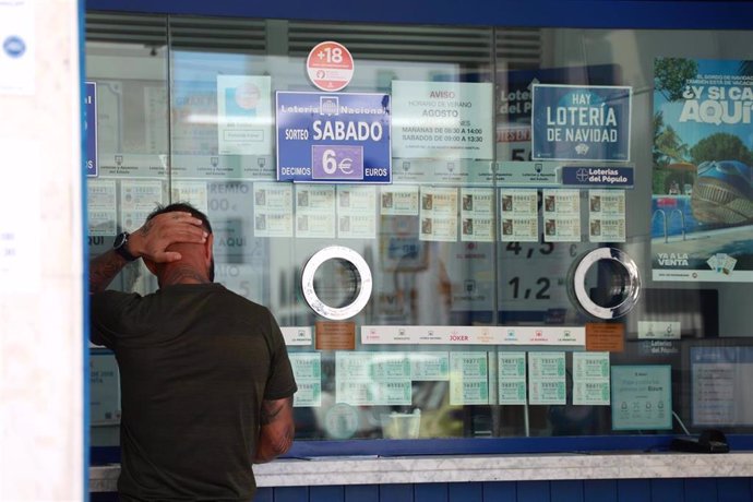 Archivo - Una persona se dispone a adquirir un boleto en una administración. Imagen de archivo