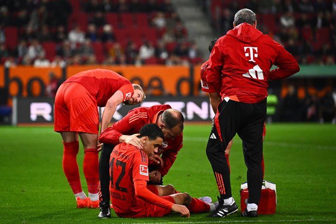 04 April 2025, Bavaria, Augsburg: Munich's Jamal Musiala receives treatment on the ground by team doctor Dr. Jochen Hahne (C) during the German Bundesliga soccer match between FC Augsburg and Bayern Munich at WWK-Arena. Photo: Tom Weller/dpa - IMPORTANT N