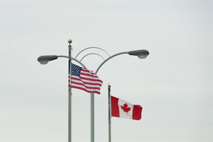 15 de março de 2025, Niagara Falls, Ontário, Canadá: Bandeiras americanas e canadenses tremulam lado a lado no lado americano da passagem de fronteira da Rainbow Bridge. Isso ocorre em meio a relações extraordinariamente tensas entre o Canadá e os EUA apó