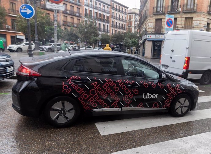 Archivo - Un vehículo con licencia VTC circula por una calle de Madrid