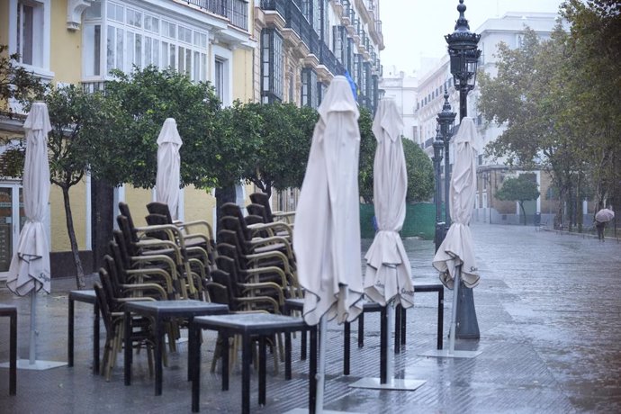 Archivo - Veladores recogidos durante la intensa lluvia. A 11 de octubre de 2024, en Cádiz (Andalucía, España). La Agencia Estatal de Meteorología (Aemet) ha activado para este viernes avisos de nivel naranja por lluvia y amarillo por tormenta en la mitad