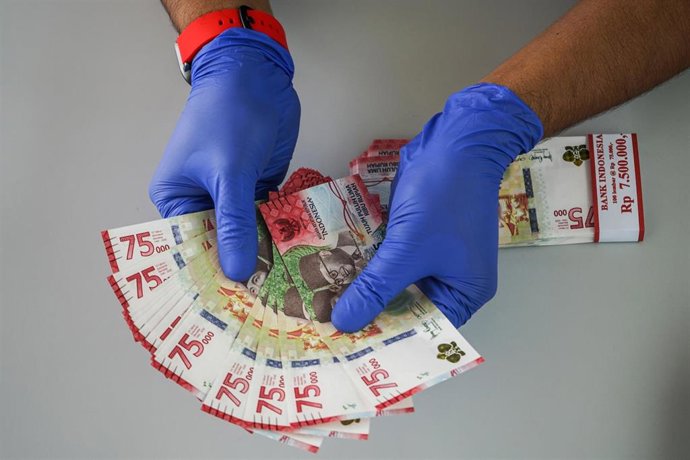 Archivo - 18 August 2020, Indonesia, Makassar: A bank employee shows the new 75,000 rupiah commemorative banknotes, issued to commemorate Indonesia's 75th Independence anniversary. Photo: Herwin Bahar/ZUMA Wire/dpa