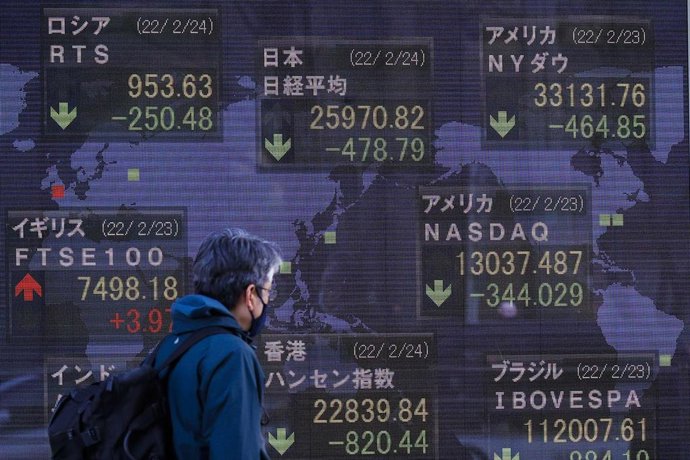 Archivo - 24 February 2022, Japan, Tokyo: A man walks past an electronic stock exchange board displaying Japan's Nikkei stock index in downtown Tokyo. Japan's Nikkei index fell below 26,000 points on Thursday for the first time since November 2020 after R