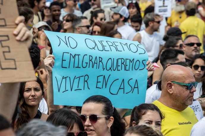 Archivo - Una persona sujeta un cartel de protesta durante una manifestación contra el modelo turístico en Canarias