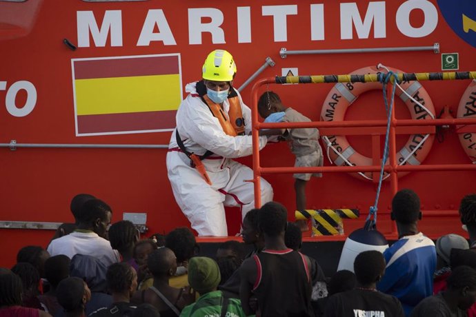 Archivo - Una persona de Salvamento Marítimo ayuda a un menor, en el Puerto de la Restinga