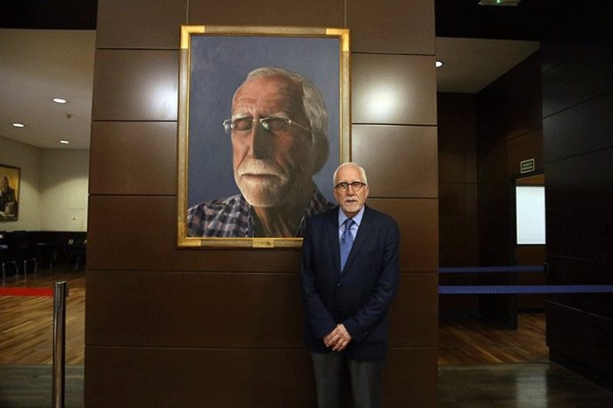 El escritor posa junto al retrato realizado por Jorge Diezma.