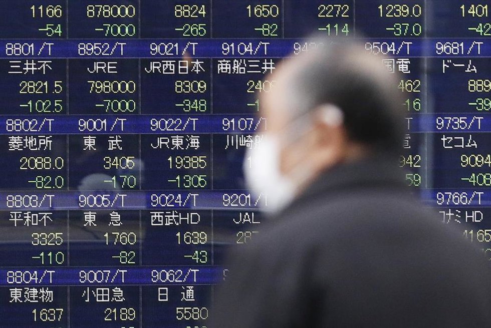 Archivo - 25 February 2020, Japan, Tokyo: A man wearing a surgical mask walks past an electronic stock board showing Japan's Nikkei Stock Average, which dropped nearly 1,000 points in early Tuesday trading to its lowest level since mid-October due to co