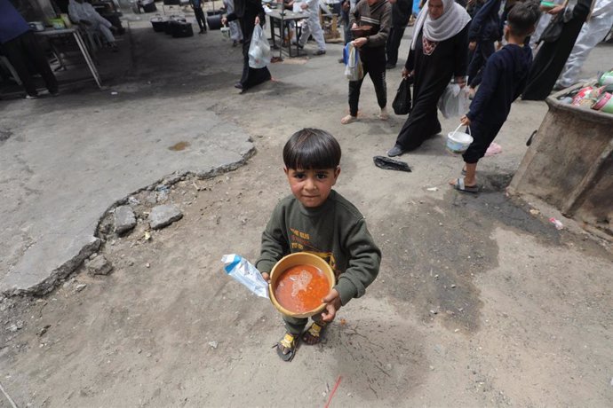 Palestinos, entre ellos un niño, acuden a recoger alimentos en el campamento de refugiados de Nuseirat, situado en el centro de la Franja de Gaza, en medio de la ofensiva militar de Israel (archivo)