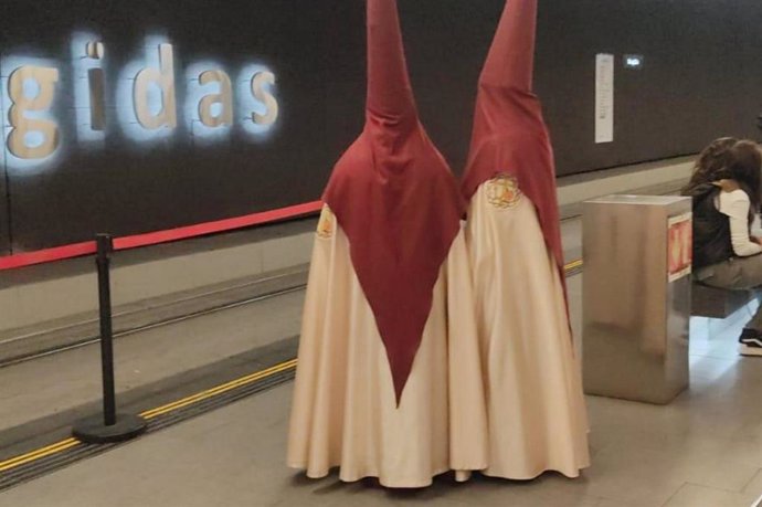Dos nazarenos esperan el metro en la estación de Recogidas