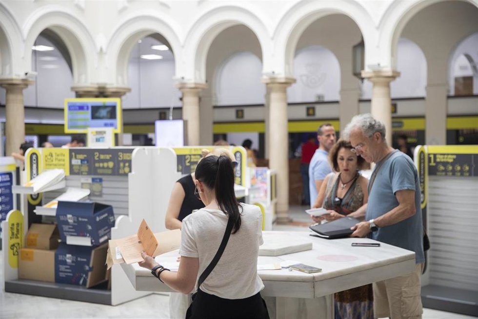 Archivo - Varias personas en los mostradores de la oficina de Correos de la Avd. de la Constitución