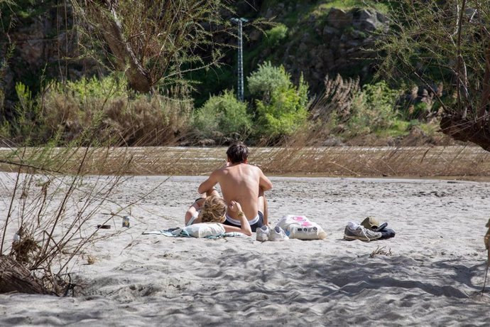 Dos personas en la playa del río Tajo, a 6 de abril de 2025, en Toledo, Castilla-La Mancha (España). Tras el episodio de crecida del río Tajo por las lluvias de finales del pasado mes de marzo, ha emergido a los pies del Casco Histórico de Toledo una play