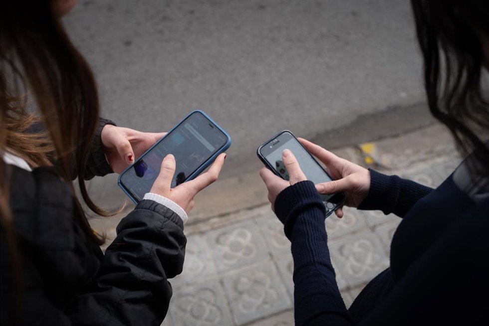 Archivo - Dos personas usan el teléfono móvil, a 1 de febrero de 2024, en Barcelona, Catalunya (España). El pasado 30 de enero el Govern aprobó las instrucciones que regulan el uso de los dispositivos móviles en las aulas de colegios e institutos, que s
