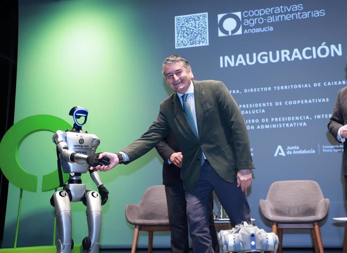 El consejero de la Presidencia, Interior, Diálogo Social y Simplificación Administrativa, Antonio Sanz, saluda a un robot durante la inauguración de la jornada IA. A 08 de abril de 2025, en Sevilla (Andalucía, España). 