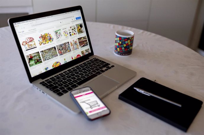 Archivo - Una persona compra con su teléfono móvil y ordenador el día en que dan comienzo las Rebajas Online, a 3 de enero de 2022, en Madrid, (España). 