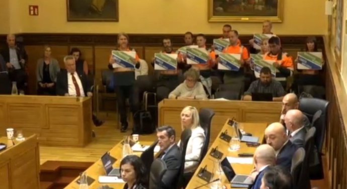 Trabajadores de Emulsa exhiben carteles de protesta durante el Pleno Municipal de Gijón.