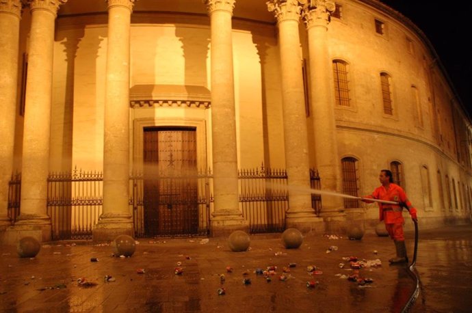 Archivo - Un operario de Sadeco baldea la calle junto a la iglesia de Santa Victoria , en una imagen de archivo.