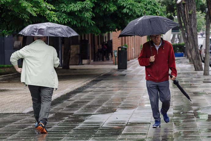 Archivo - Dos personas pasean bajo la lluvia, a 23 de mayo de 2023, en Madrid (España). 