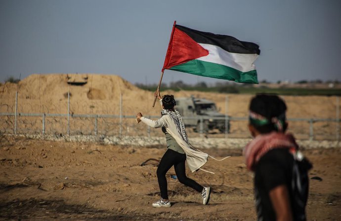Archivo - 16 de agosto de 2019, Gaza, khan younis, Palestina: Um manifestante palestino agita a bandeira palestina durante confrontos entre manifestantes palestinos e forças israelenses do outro lado da cerca entre Gaza e Israel, perto de Khan Younis, no 