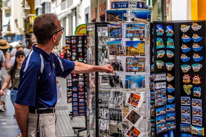 Archivo - Un turista mira una tienda de recuerdos en Cádiz.