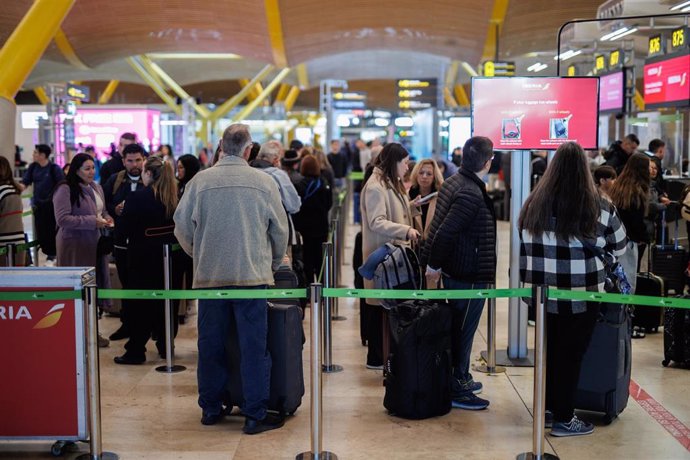 Archivo - Varias personas con maletas hacen cola en la terminal T4 del aeropuerto de Adolfo Suárez-Madrid Barajas