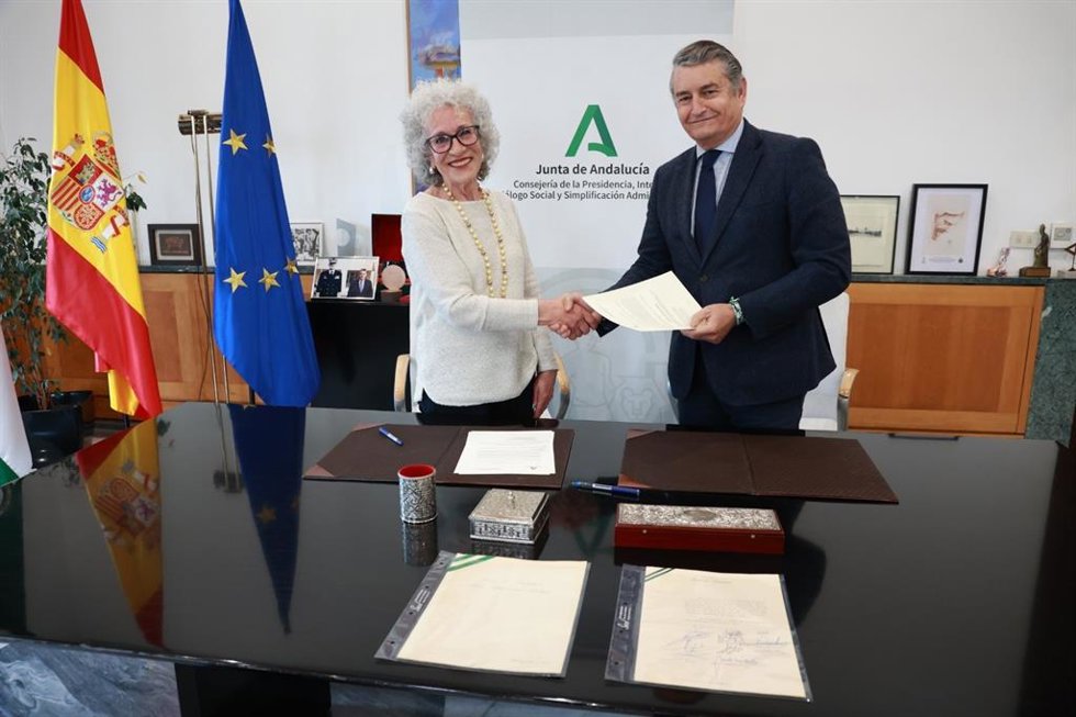El consejero de la Presidencia, Antonio Sanz, estrecha la mano de Carmela Gálvez, quien fue secretaria de Plácido Fernández-Viagas para la donación de un ejemplar original del Pacto de Antequera.