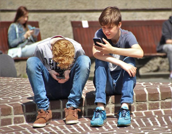 Archivo - Niños utilizando un 'smartphone'.