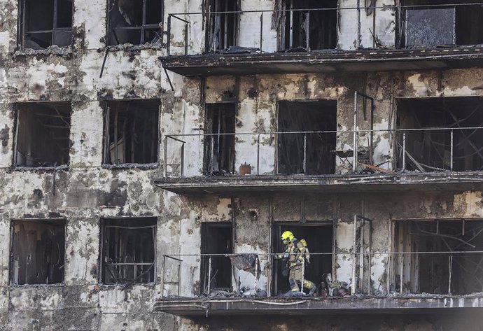 Archivo - Un agente de la Policía Científica busca las causas del incendio en el edificio del barrio de Campanar (València)