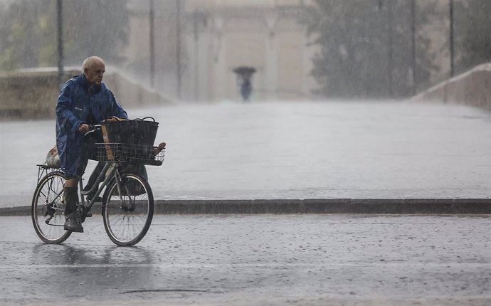Archivo - Una persona en bicicleta bajo la lluvia, a 15 de septiembre de 2023, en València