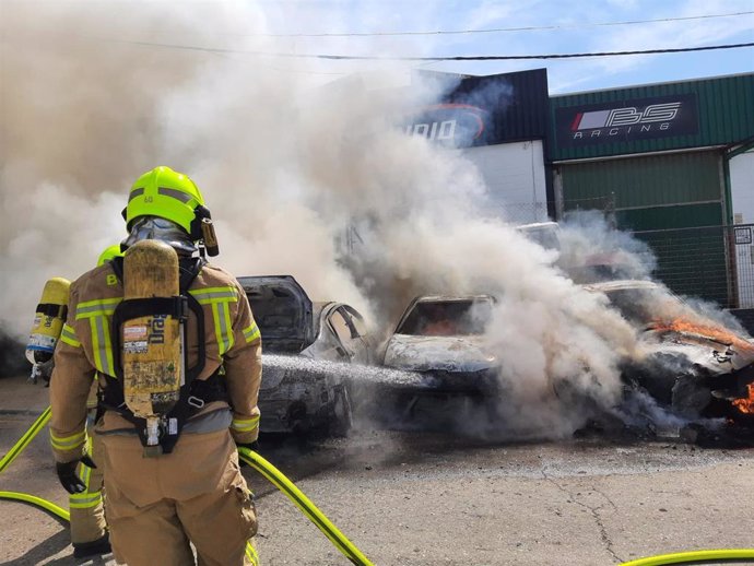 Un bombero interviene para sofocar el fuego que ha afectado a varios vehículos