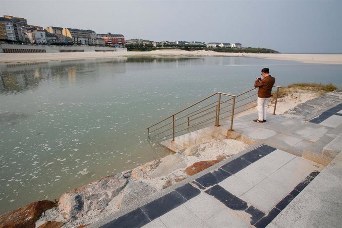 Archivo - Unha persona fotografa a pleamar no espigón de Foz, xunto á praia da Rapadoira.