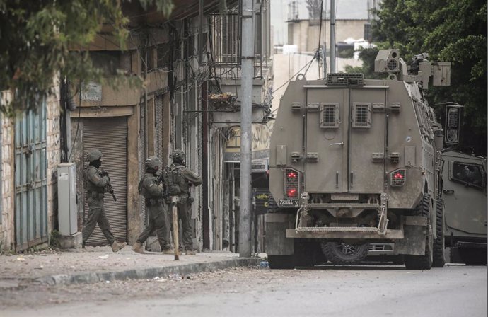 8 de abril de 2025, Nablus, Palestina: Soldados israelenses se posicionam perto de jipes militares durante uma incursão na cidade de Nablus, na Cisjordânia. As forças israelenses invadiram uma casa onde um palestino havia se refugiado, demoliram seu conte
