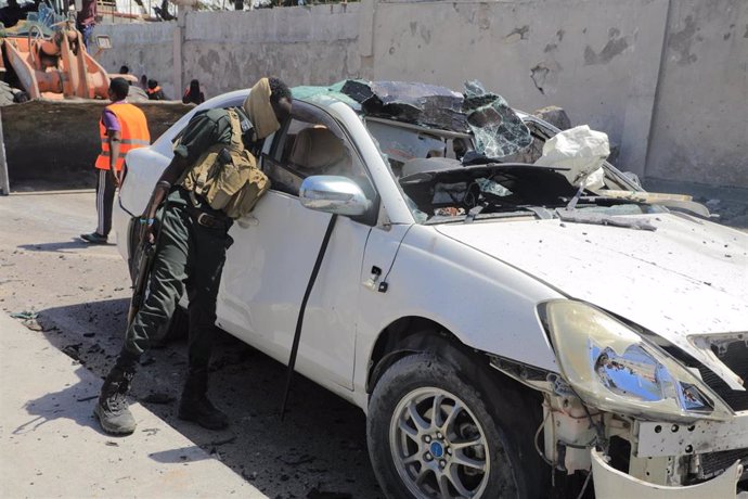 Archivo - Un miembro de seguridad revisa un vehículo en la escena de un ataque suicida con coche bomba en Mogadiscio, Somalia (archivo)