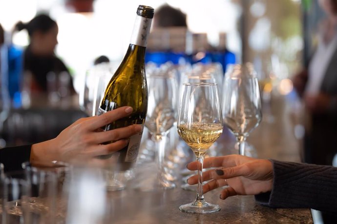 Archivo - Un camarero sirve copas de vino blanco en un bar.