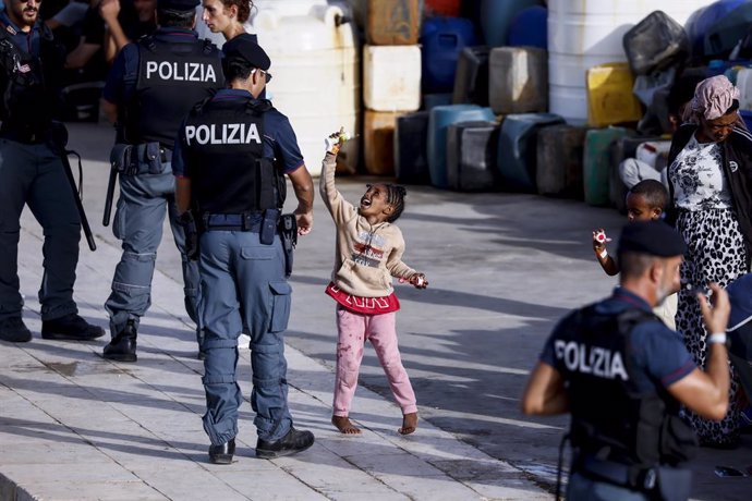 Archivo - Arquivo - 18 de setembro de 2023, Itália, Lampedusa: Uma menina brinca com um policial perto de um centro operacional na ilha italiana de Lampedusa. Um grande número de migrantes da África chegou à ilha do Mar Mediterrâneo esta semana. Foto: Cec