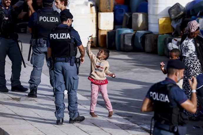 Archivo - Arxiu - Una xiqueta juga amb un policia a Lampedusa, Itàlia
