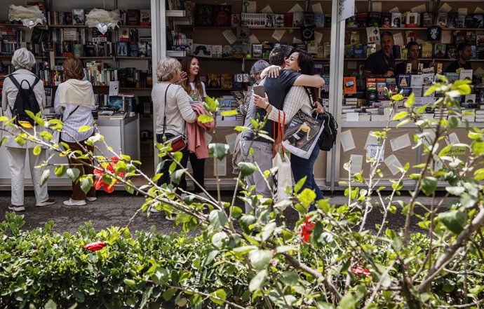 Archivo - Varias personas miran libros en una caseta el día de la inauguración de la Fira del Llibre de Valencia