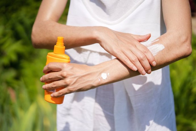 Archivo - Joven aplicándose crema solar.