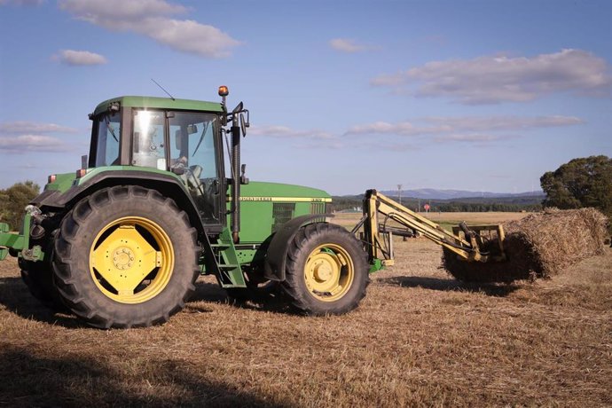 Archivo - Un tractor durante la recogida de trigo.