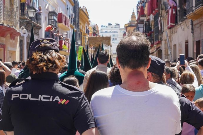 Archivo - Un costalero junto a un policía viendo la recogida de la Hermandad de la Esperanza de Triana