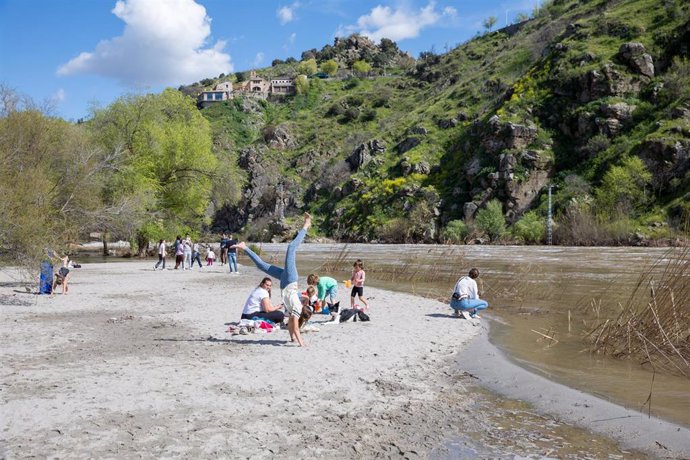 Varias personas en la playa del río Tajo en Toledo.
