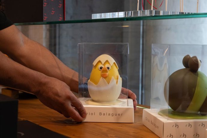 Un hombre coloca una mona de Pascua en un escaparate