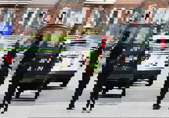 02 July 2021, US, Norfolk: Police officers stand guard at the scene where four children, between ages 6 and 16, were shot dead in Norfolk. Photo: Trent Sprague/Zuma Press/dpa