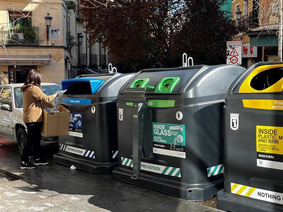 Una vecina tira residuos en uno de los contenedores de la nueva campaña de conciención del Ayuntamiento de Madrid