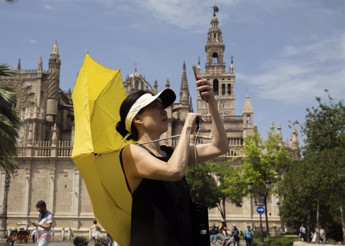 Archivo - Turista se protege de sol con un paraguas. A 28 de abril de 2023, en Sevilla.